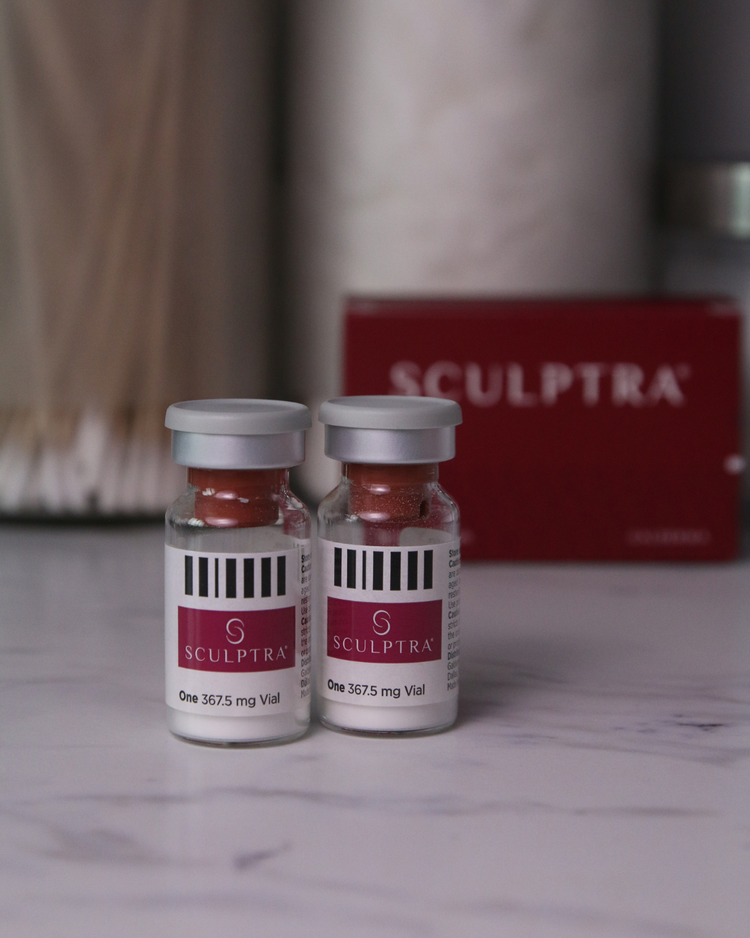 Two Sculptra vials on a marble surface with a blurred background